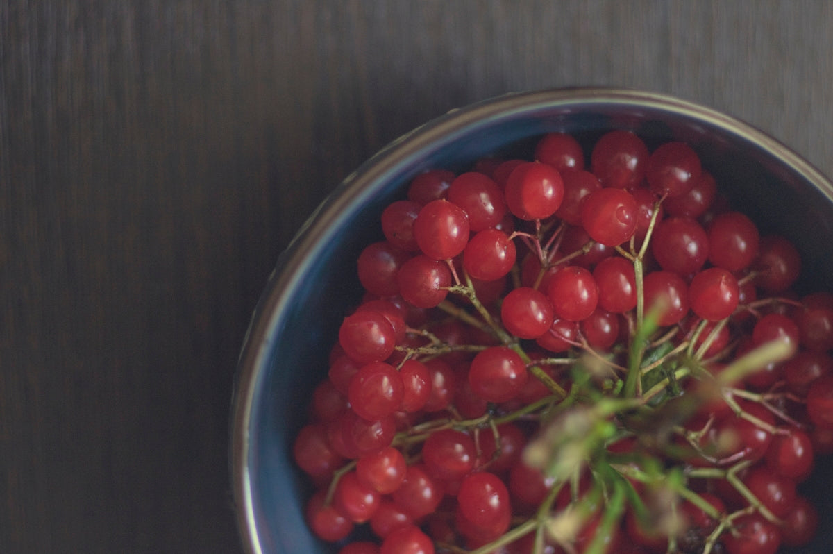a blue bowl filled with red berries on top of a table