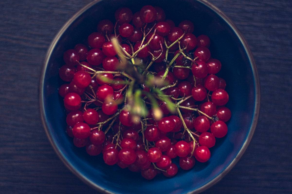 a blue bowl filled with red cherries on top of a wooden table