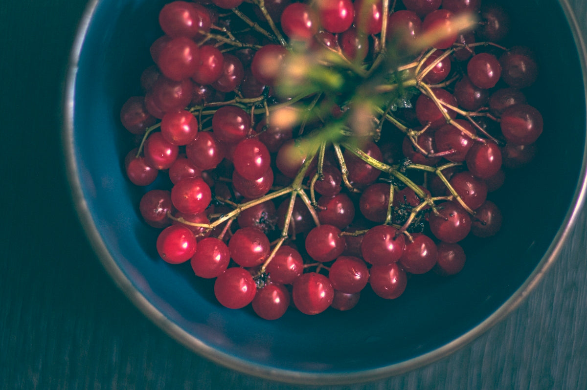 a blue bowl filled with red berries on top of a table