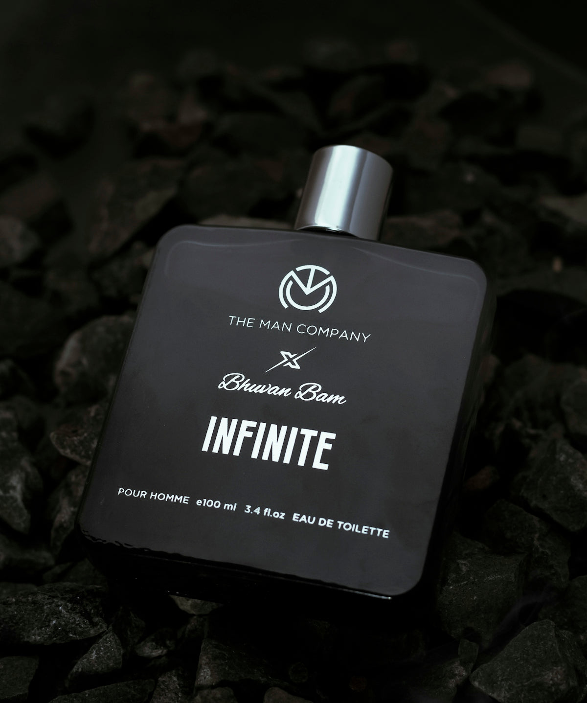 a bottle of perfume sitting on top of a pile of rocks